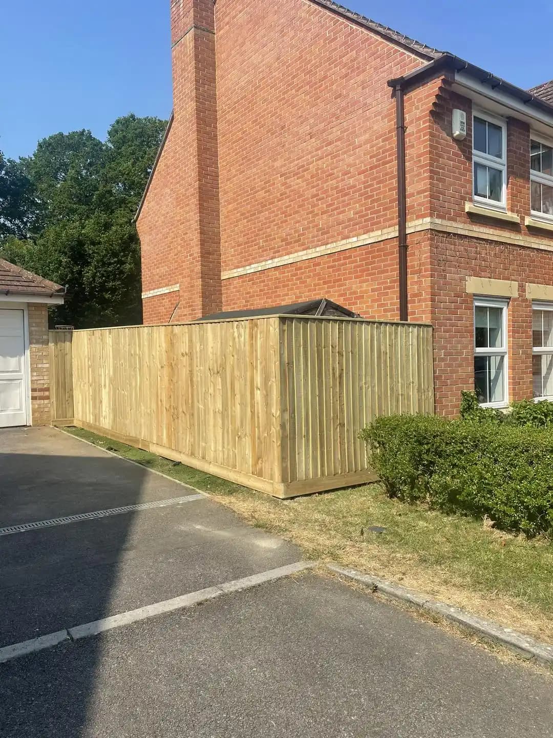 Closeboard fencing forming a neat corner boundary beside a brick house and driveway.