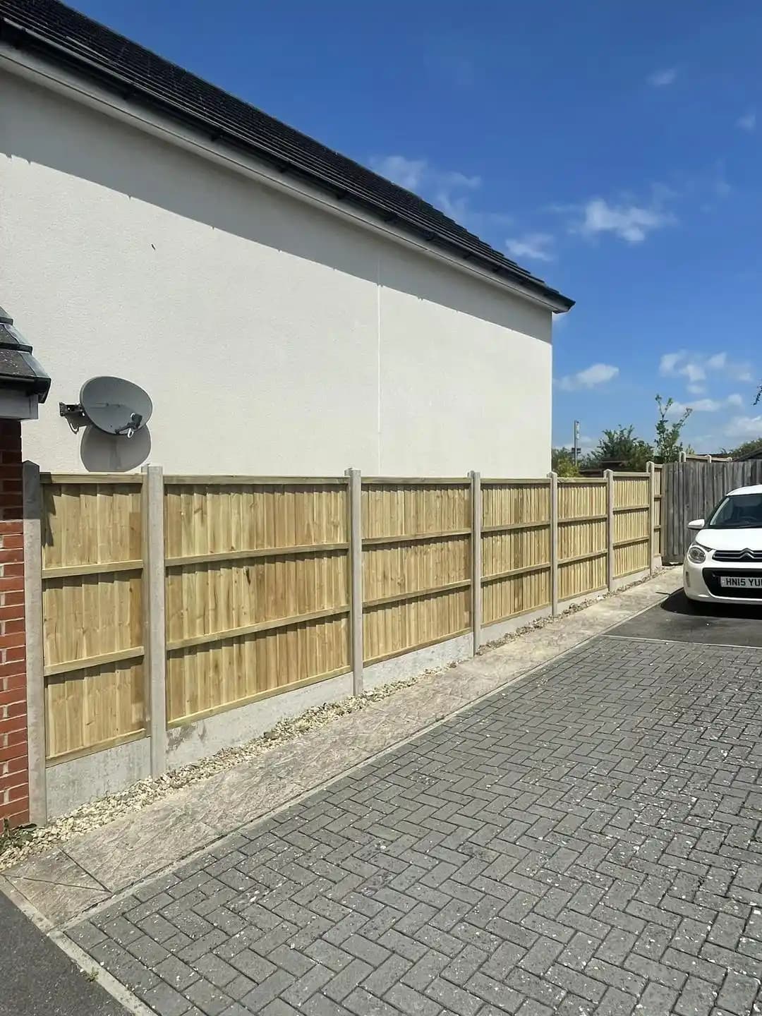 Closeboard fence panels set between concrete posts along a driveway and side boundary.