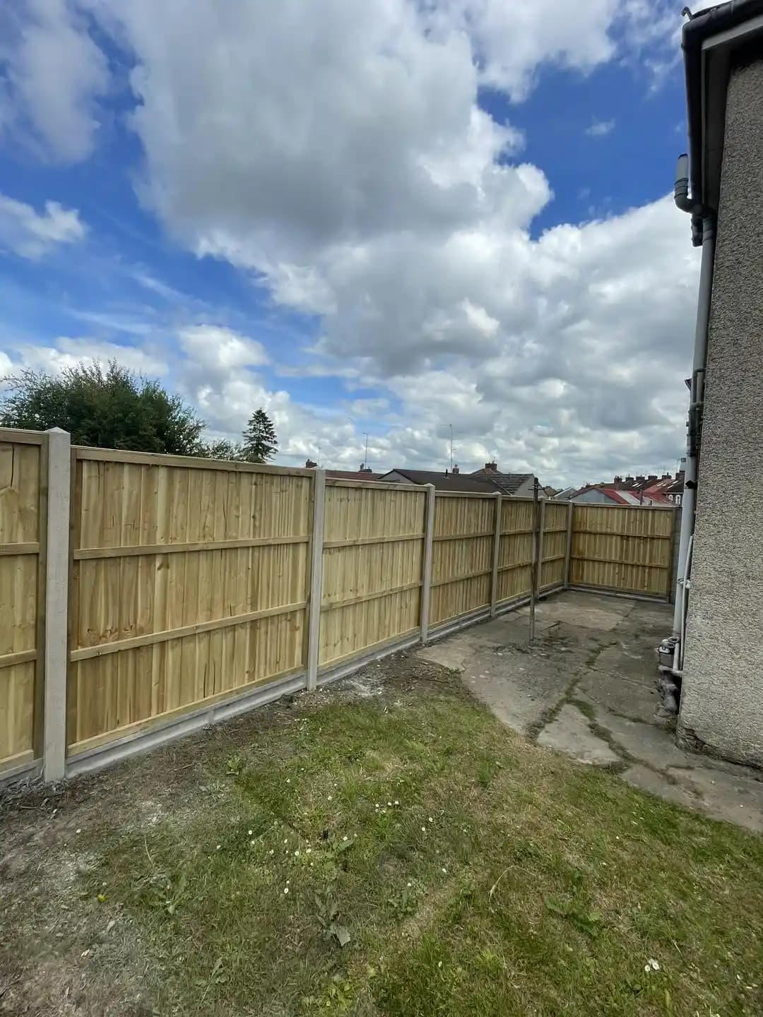Closeboard timber fence with concrete posts enclosing a side garden and lawn area.