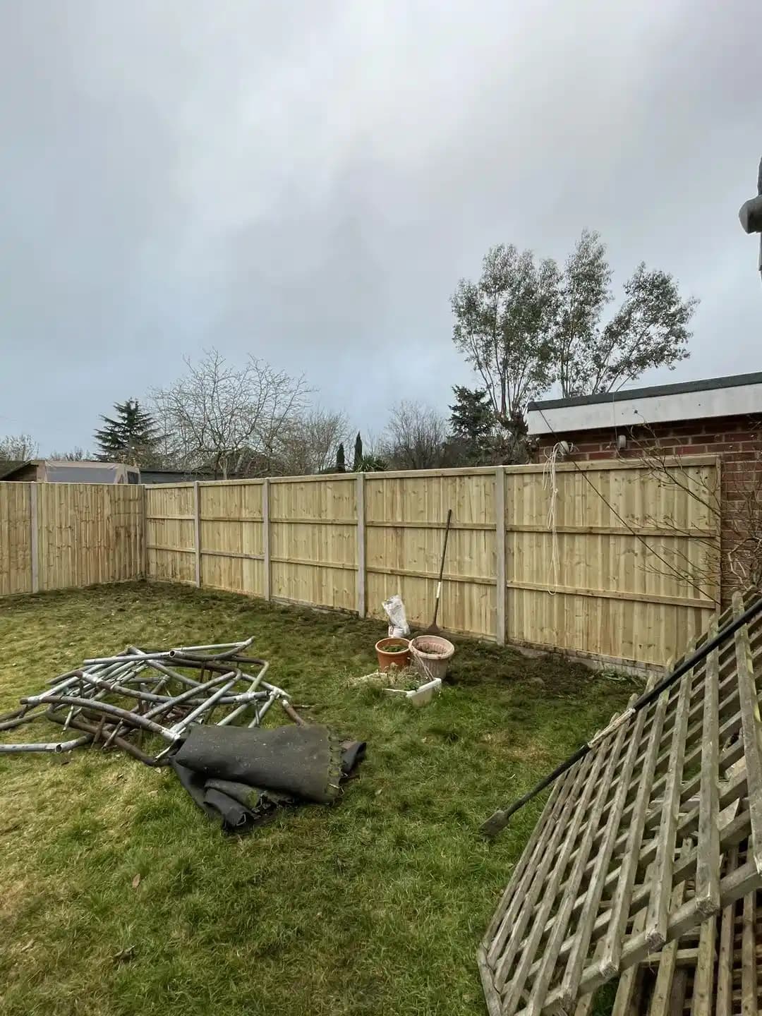 Closeboard timber garden fencing installed along a lawn with trellis panels and materials.