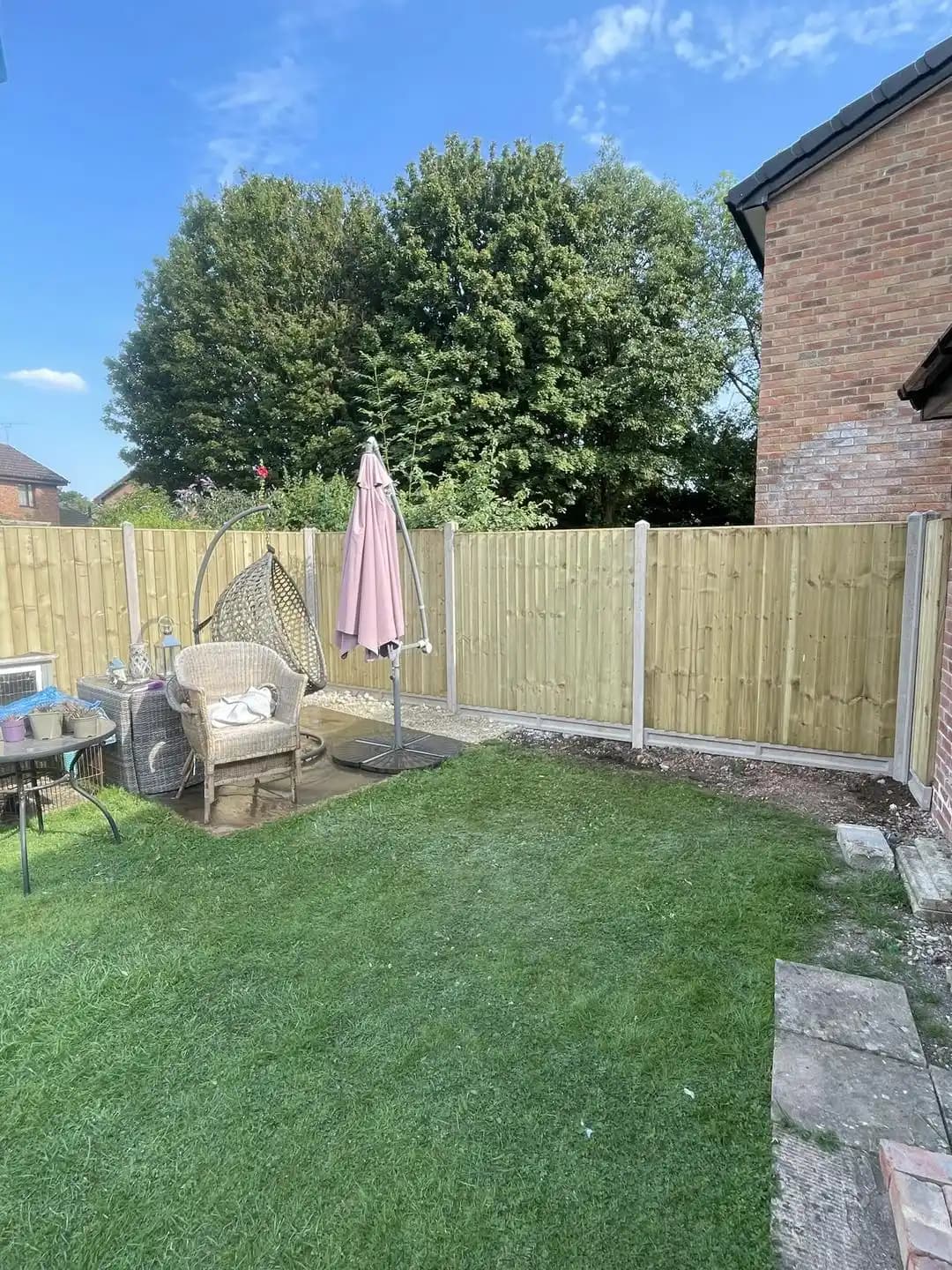 New closeboard fence panels with concrete posts installed around a lawn and garden seating area.
