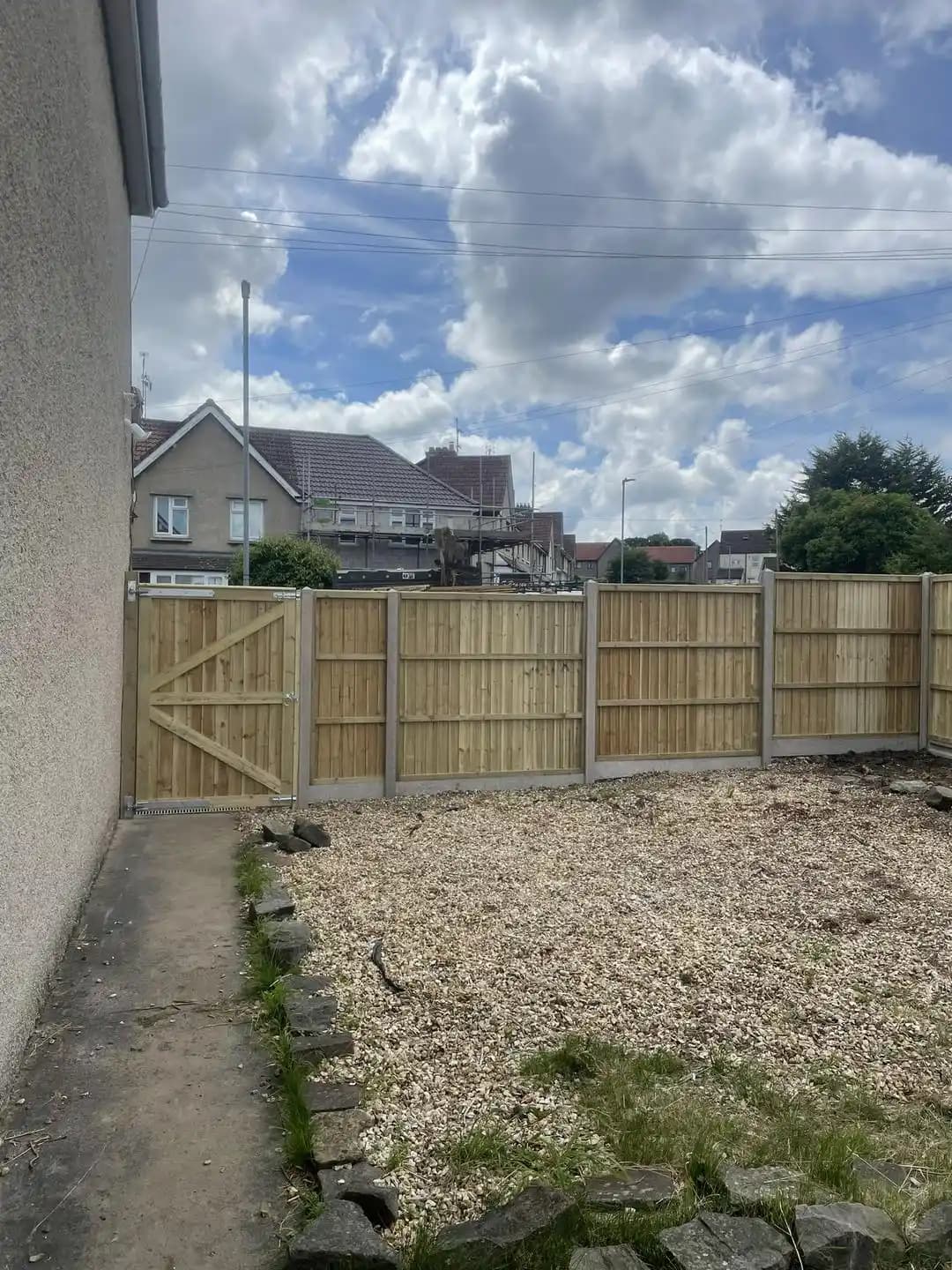 Closeboard timber fence panels and gate installed around a gravel garden area with concrete posts.
