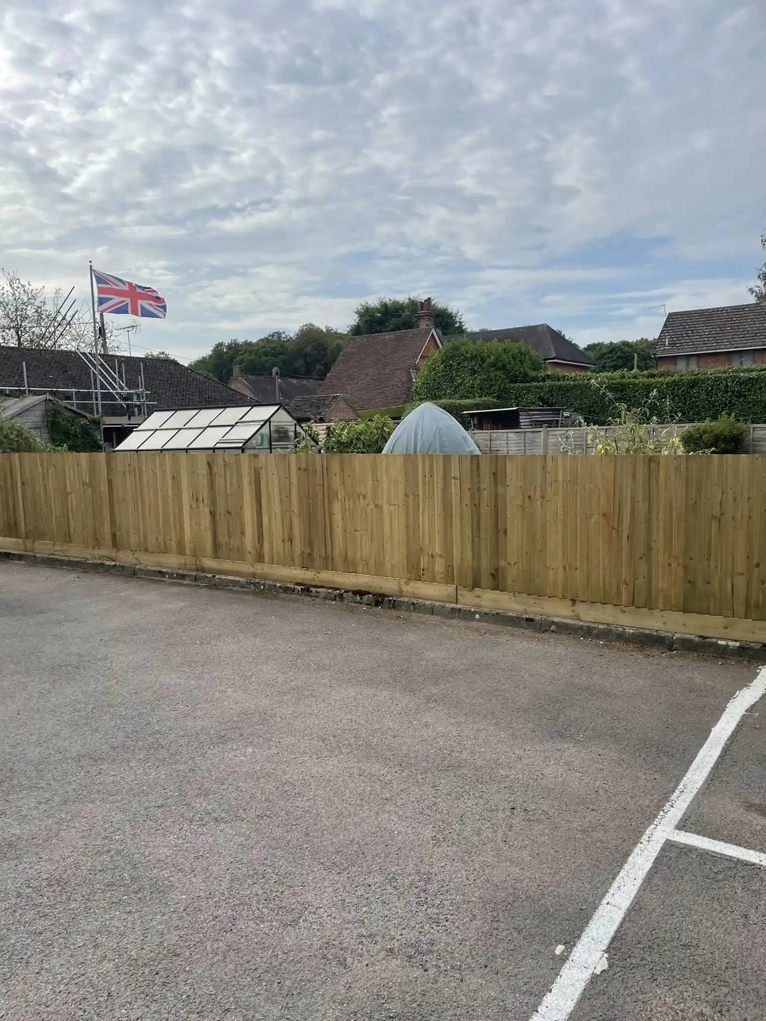 Long new closeboard timber fence installed along a car park boundary near homes.