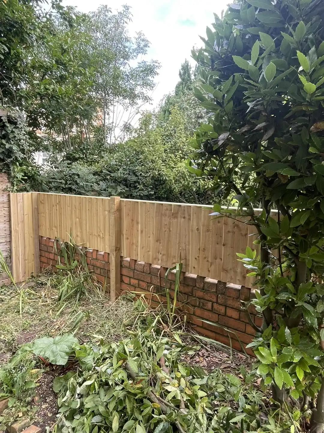 Closeboard timber fencing fitted above a brick garden wall after border clearance.