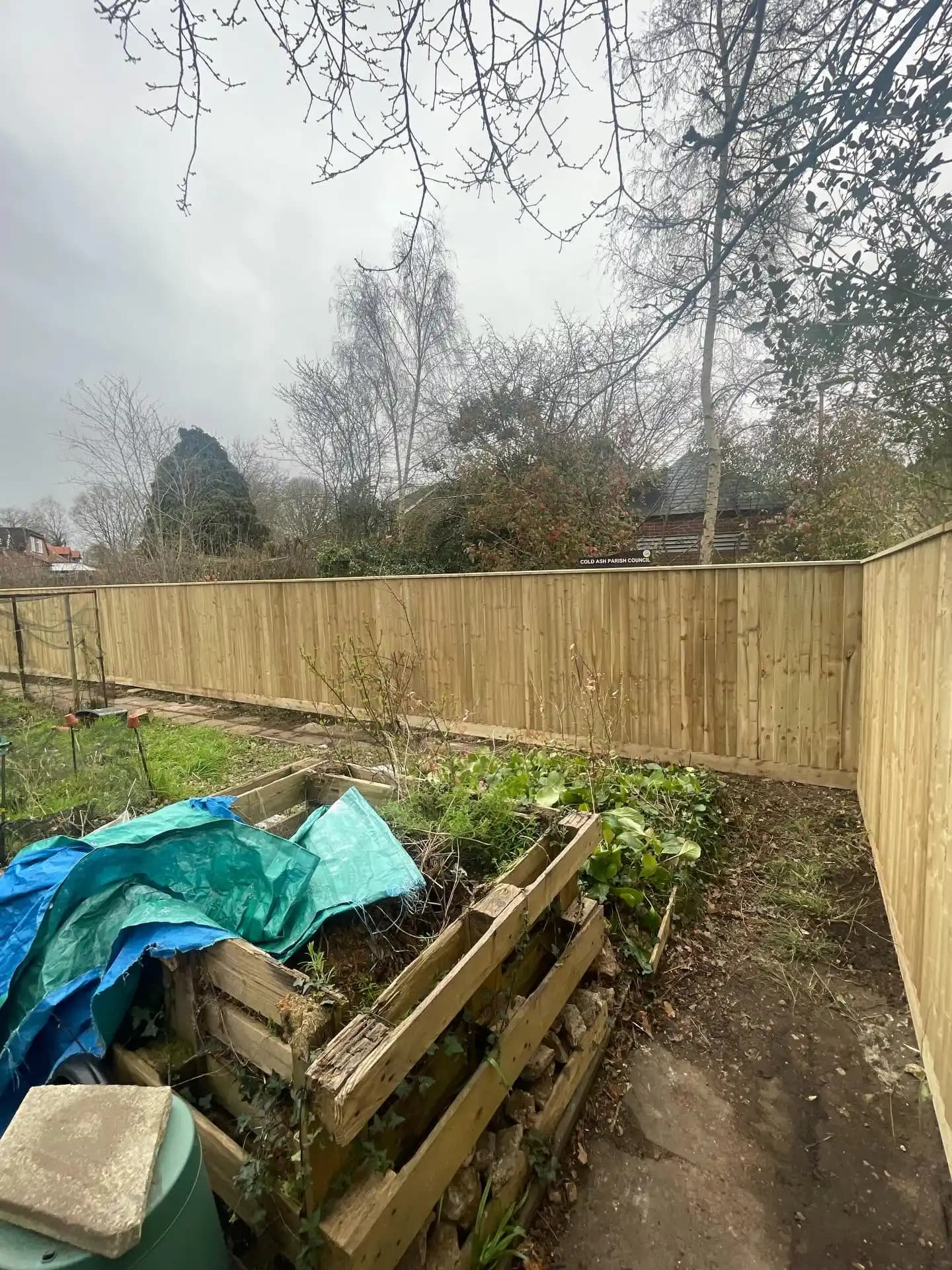 New closeboard timber garden fence with capping installed around a vegetable garden.