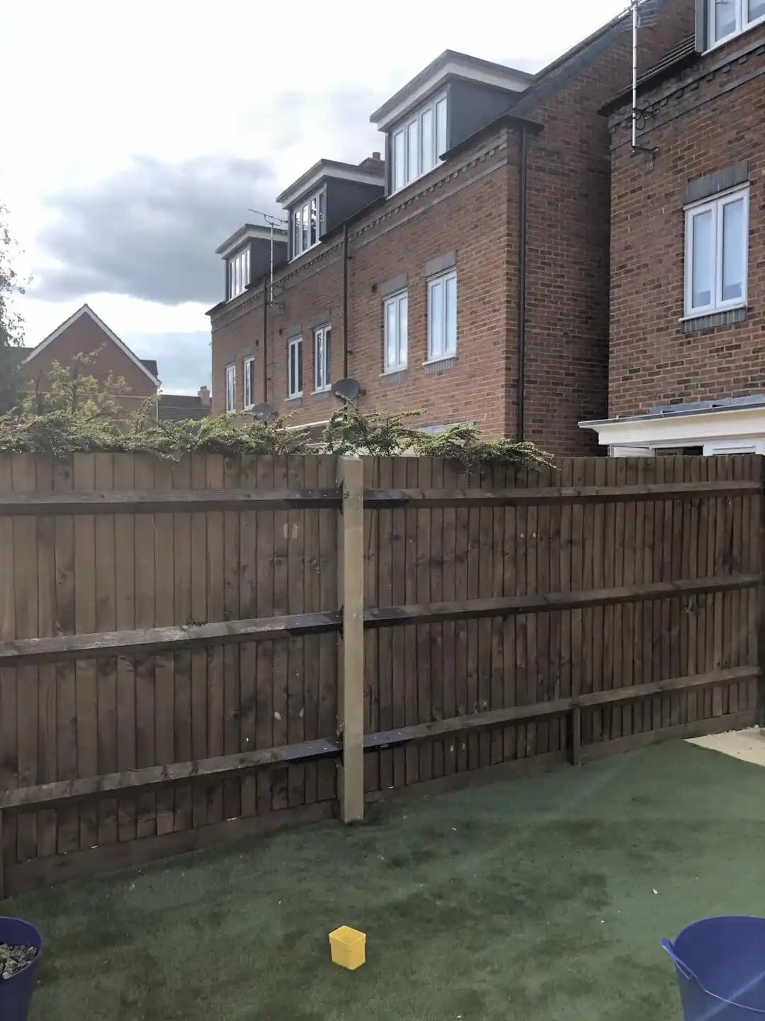 Existing dark stained timber boundary fence with a new timber post added before further replacement work.