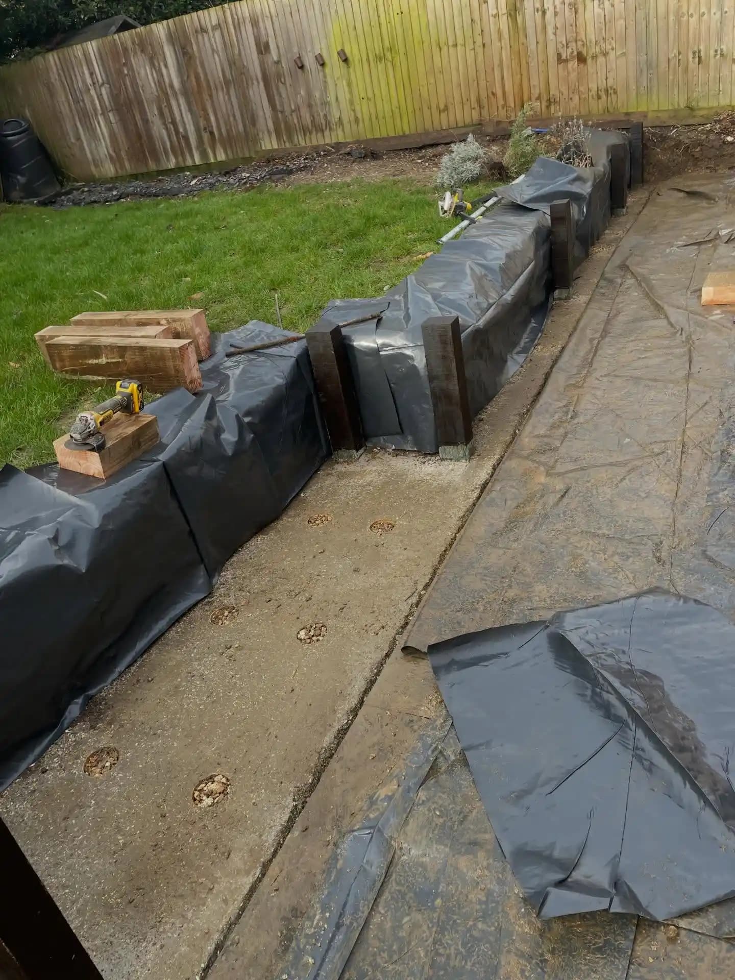 Close-up of neatly finished timber sleeper retaining wall, steps and decorative gravel beside grey porcelain paving.