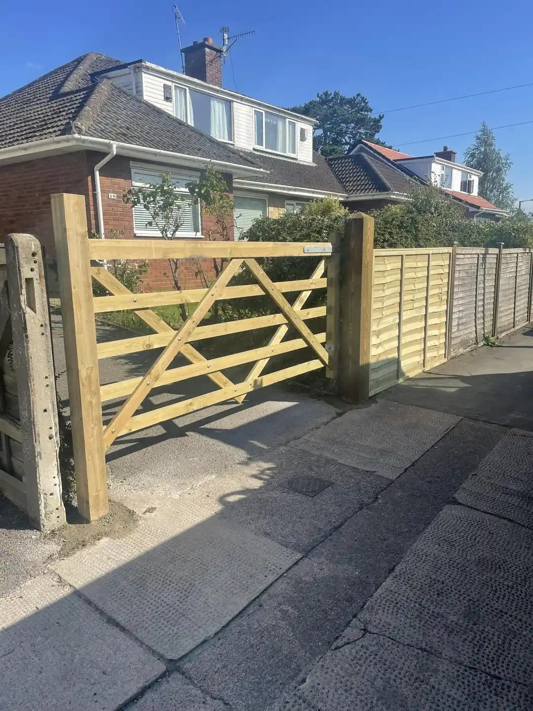 Timber five bar driveway gate installed beside closeboard fencing at the front of a house.