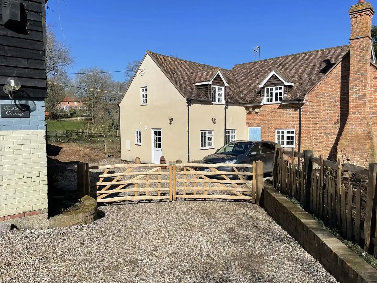 Pair of timber five bar driveway gates installed at a gravel entrance to a cottage property.