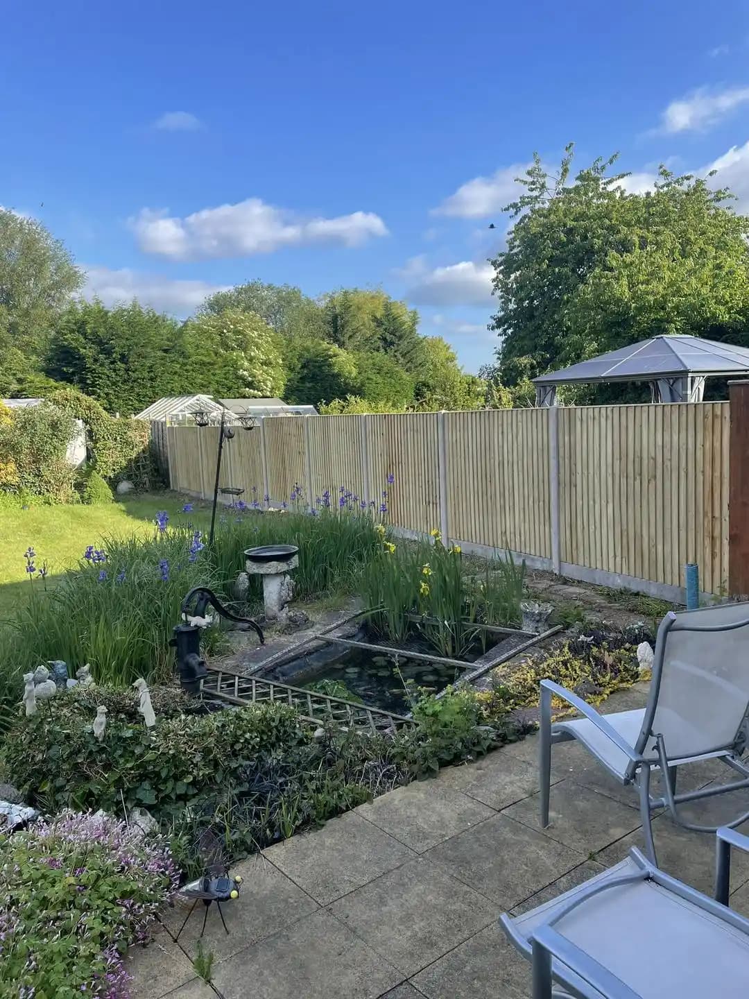 Garden pond and patio seating area with a new closeboard fence forming the rear boundary.