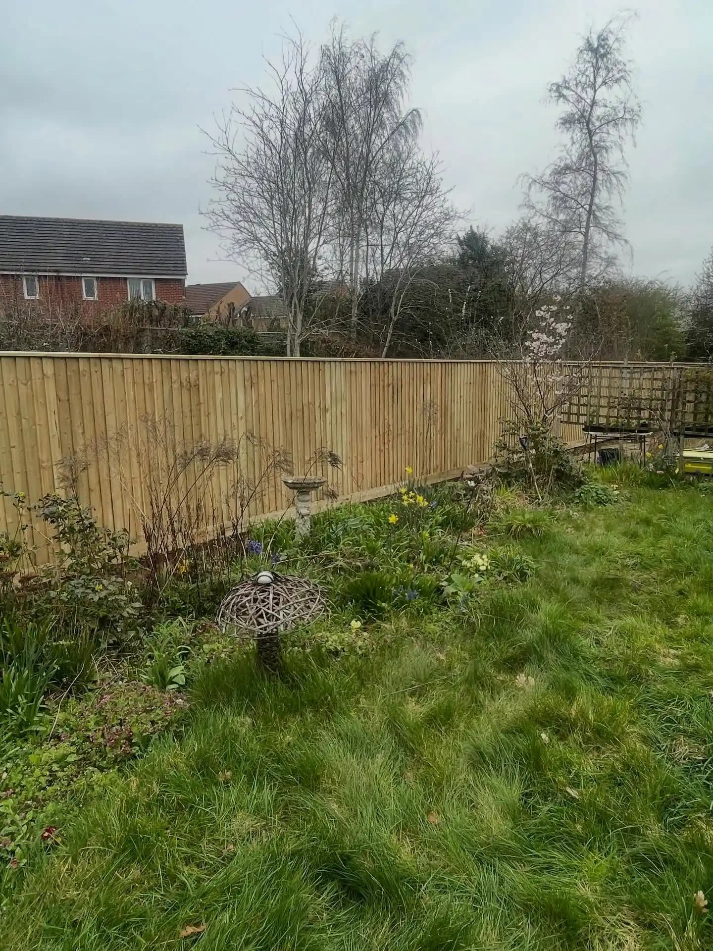 Timber sleeper retaining wall under construction beside a paved patio, ready for garden landscaping.
