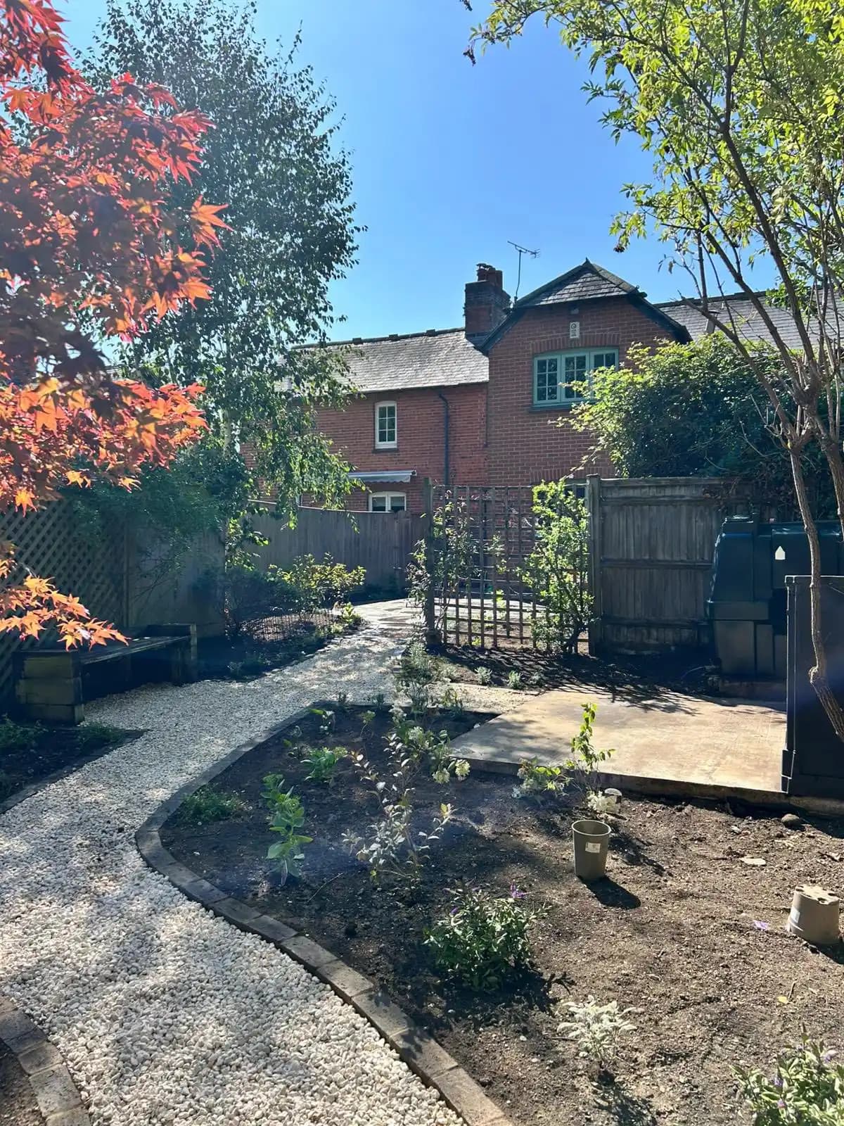 White gravel path with curved edging, new planting borders and trellis screens for a tidy landscaped garden.