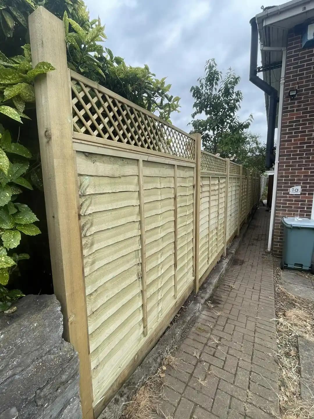 Closeboard fence panels with a lattice trellis top installed along a side access walkway.