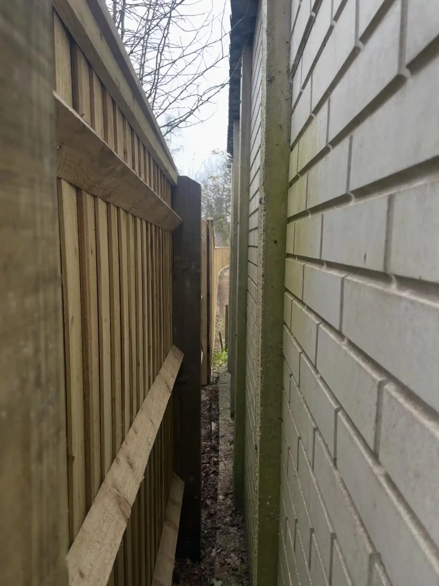 Closeboard timber fencing installed along a narrow side passage beside a property wall, showing neat posts and rails.