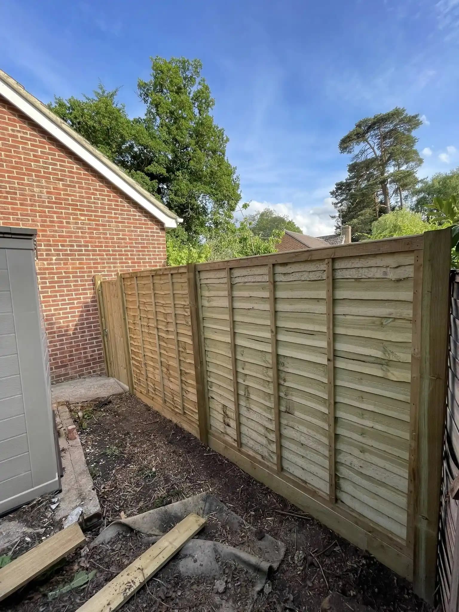 Fresh closeboard fence panels and posts installed beside a garage and garden path.