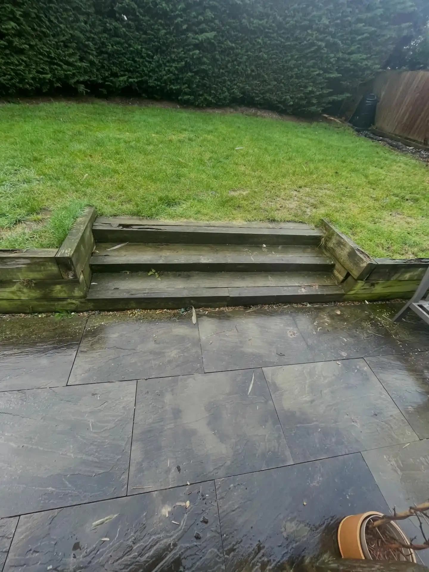 Freshly built timber sleeper steps and retaining wall linking a porcelain patio to a raised lawn area.