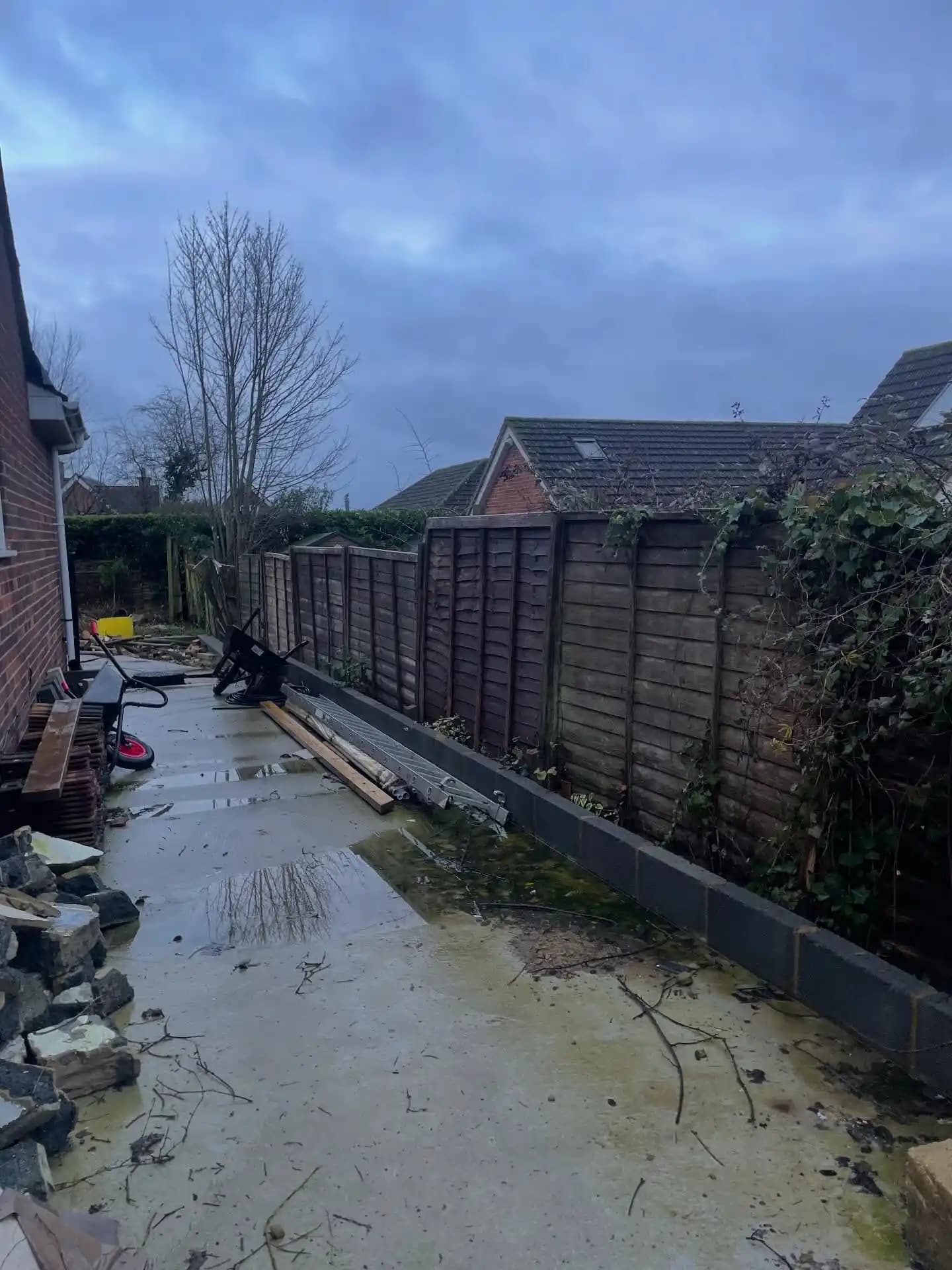 Fresh trellis top fence panels fitted beside a concrete patio base as part of a garden boundary replacement.
