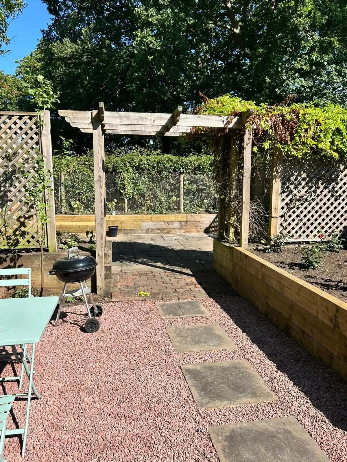 Levelled soil and porcelain paving before turfing and final planting in a back garden landscaping project.