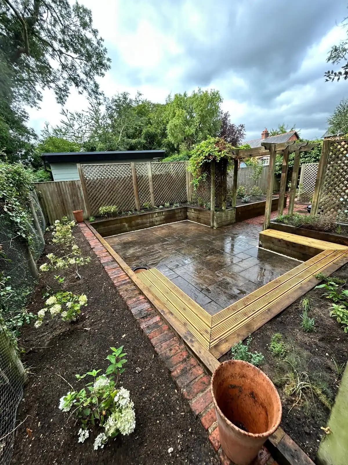 New patio area with raised timber beds, trellis screening, brick edging and fresh planting after a garden makeover.