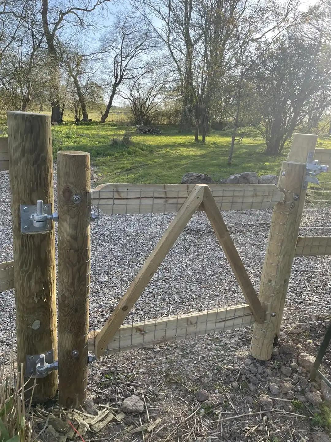 Timber field gate with wire mesh fitted between sturdy posts for a rural garden or paddock entrance.