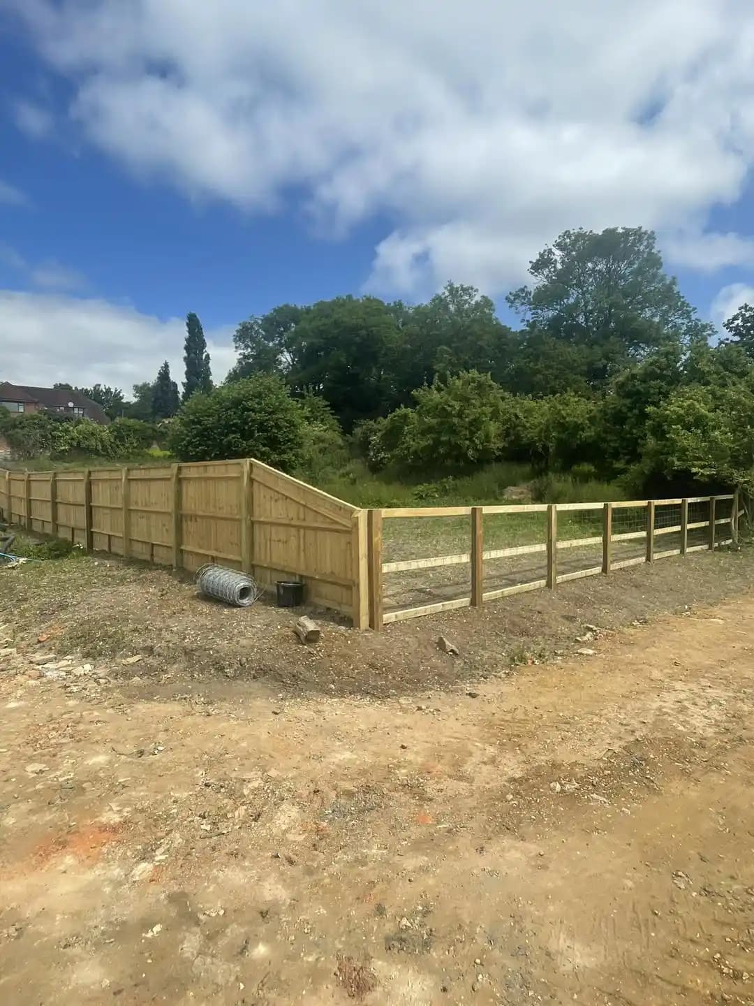 Combination of closeboard fencing and post and rail fencing installed around a large garden plot.