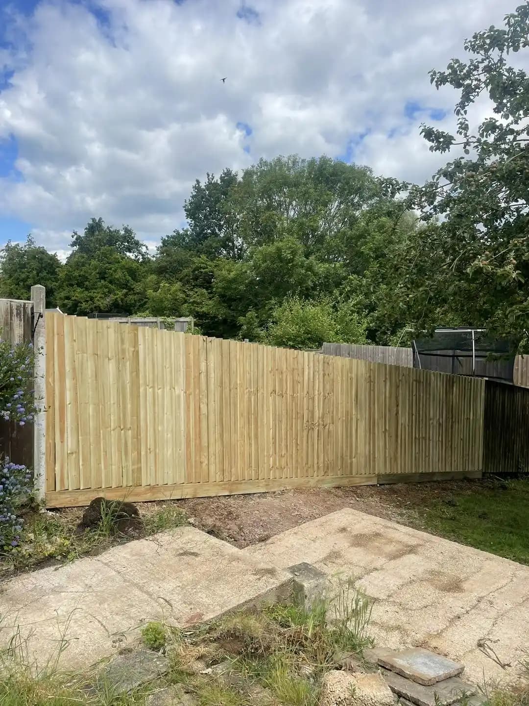 Tall new closeboard timber fence enclosing a patio and garden boundary.