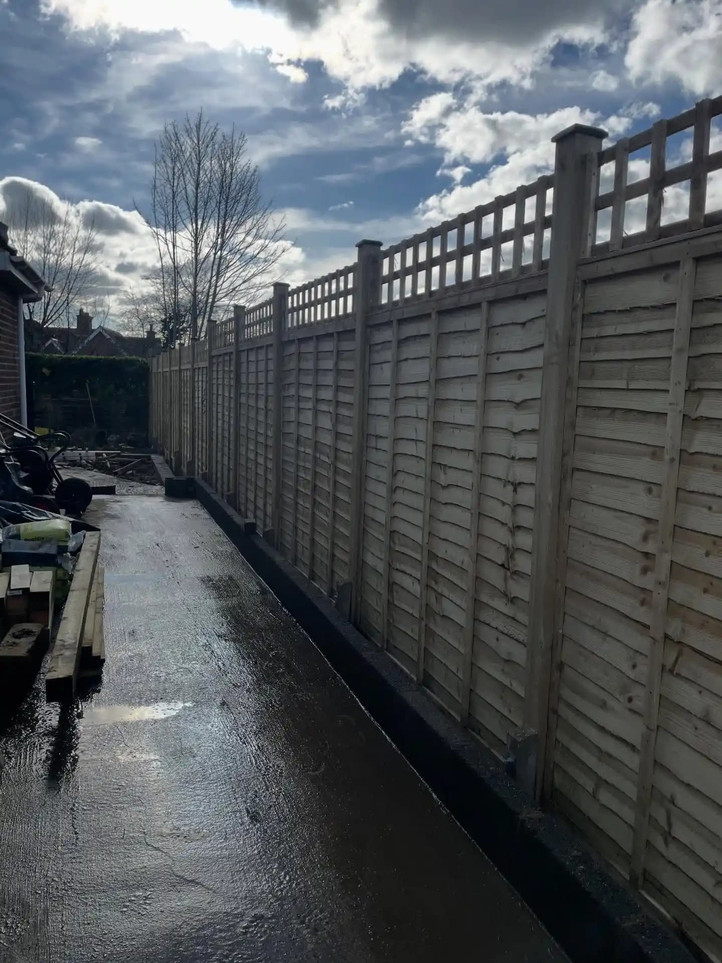 New timber garden fencing with trellis top panels and posts creating privacy beside a house.