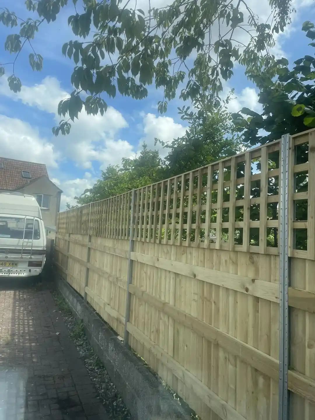 Timber closeboard fence with lattice trellis top installed along a driveway beside a property.